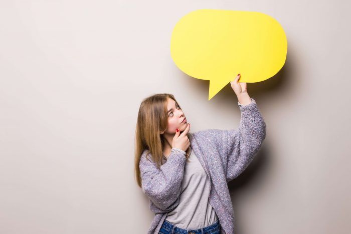 Mujer joven sosteniendo una burbuja de dialogo y practicando su pronunciacion alemana